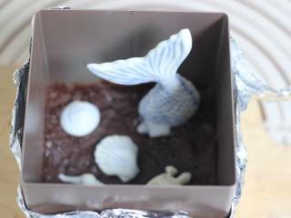 6、海底世界果冻,巧克力隔水融化，然后用刷子刷在压实的饼干碎上层！刷均匀一点，让饼干碎的上层形成一层巧克力！