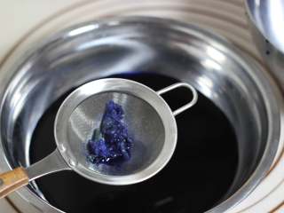7、海底世界果冻,泡软的吉利丁隔水融化，分成四到五份！将泡好的蝶豆花茶用筛子过滤出蝶豆花不要！喜欢吃甜的，可以在茶中加适量白砂糖，甜度完全自己掌握即可，搅拌至砂糖融化