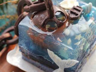 12、海底世界果冻,脱模时因为这个完全和果冻一样！没有任何的淡奶油或者奶酪在里边！所以难度要稍微大一点！先去掉慕斯圈下层的保鲜膜和锡纸！将慕斯圈放到一个比慕斯圈稍微小一点的杯子或者其他合适的容器上，用热毛巾捂住蛋糕模四周，焐热以后，轻轻的向下脱慕斯圈！最后把果冻拿出来即可！