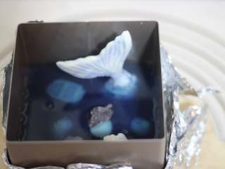 10、海底世界果冻,然后放几颗贝壳，倒入第二份吉利丁溶液！继续冷冻凝固（冷冻时间不要长，只要蝶豆花茶凝固即可）~做第三层的时候，我就放入了做好的巧克力漂浮球，放贝壳，倒第三份蝶豆花茶。冷冻凝固！最后做最后一层！如果觉得模具不够满的话，继续放蝶豆花茶吉利丁溶液！操作过程中吉利丁凝固的话，稍微隔水加热一下即可