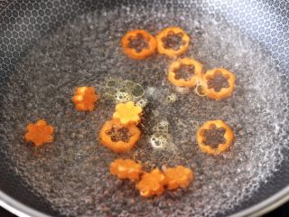 5、虾仁清炒西兰花便当,锅中倒入适量的清水，倒入几滴食用油煮沸后，放入胡萝卜片焯水。