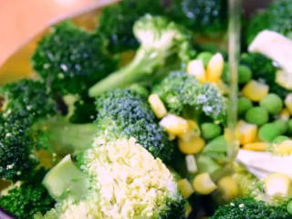 5、节日气氛浓厚的西兰花圣诞树,倒入玉米粒、青豆,再加入盐、橄榄油、黑胡椒调味,焯熟捞出备用