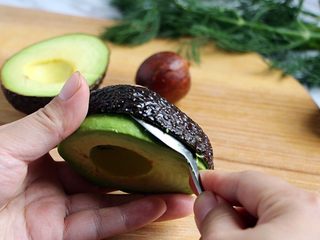 4、绿色美食+烟熏三文鱼牛油果沙拉,用勺贴着牛油皮果取出果肉，一般熟了的牛油果皮，直接剥也能去掉，操作如图。