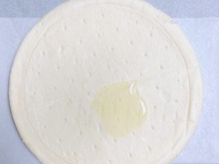 6、蜜瓜蔬果披萨,披萨饼底抹上一层油，将油底面朝下，放在油纸烤盘上。