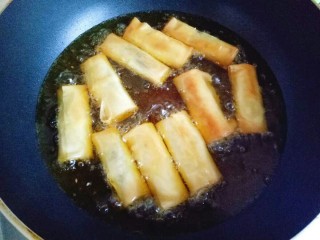 11、炸春卷,转中火，底部金黄时，用筷子翻一面，两面金黄即可捞出。