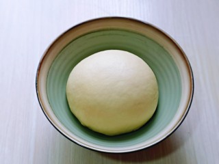 6、奶香软欧包,取出揉好的面团，再次揉圆，放入器具中。