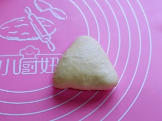9、奶香软欧包,取一块面团，捏成三角形，收口捏紧，将收口朝，稍作整形。