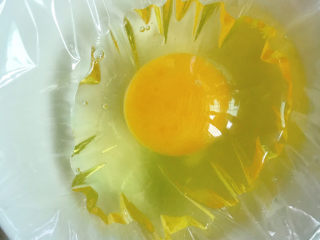 3、糖水鸡蛋,将鸡蛋打入隔了保鲜膜的碗中。