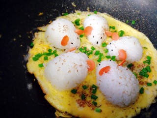 17、剩米饭百种做法+小老鼠抱蛋煎饭团,和白芝麻，盖锅盖。1分钟后，开盖，晃动一下锅，抱蛋饭团能移动，蛋饼边缘金黄，出锅。用剪成长短小段的粉丝装上胡须和尾巴。Q萌香酥的抱蛋饭团就做好了。