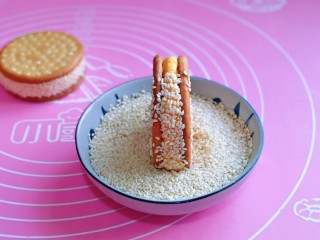 9、脆皮南瓜饼,最后裹上白芝麻，再用手轻轻拍掉多余的芝麻，南瓜面团上的芝麻捏捏紧。