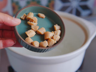 10、潮汕海鲜粥,干贝入锅同煮,干贝的鲜美会完全融入米汤中,它是这道海鲜粥的灵魂哦!(姜切丝最好,但孩子不喜欢吃出姜来,所以,我把姜切成大片,与米、干贝同时入锅,这一步竟然漏拍了)。