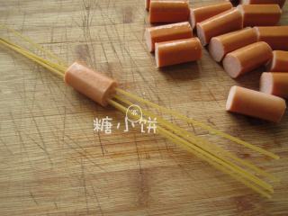 2、串肠意面,取1小段火腿肠,将干意面从中间穿入。每段火腿肠穿5-6根意面。