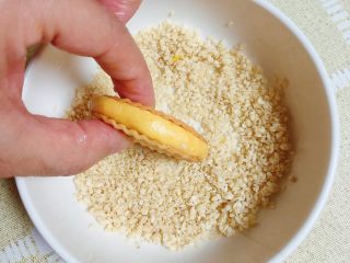 14、南瓜糯米薯片饼,将夹心饼在白芝麻碗中滚一下，粘上一圈白芝麻。