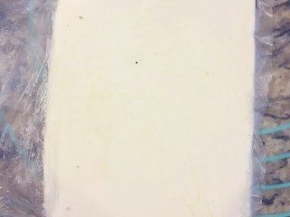 4、手撕面包,将包裹用黄油100g放入保鲜袋，擀成正方形，放冰箱冷藏