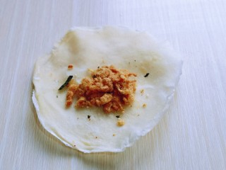 3、快手早餐～少油版香煎肉松春卷,取一张春卷皮，放上肉松。