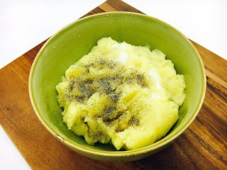 14、会跳舞的大土豆,把土豆泥放在大一点的容器里，然后放入1小勺黑胡椒粉和3个左右的盐，把他们搅拌均匀。