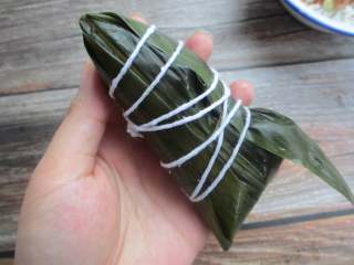 7、五花肉棕,把粽子盖上，用大拇指按住，包好后用绳捆起来