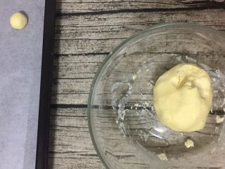 6、旺仔小馒头,取一个烤盘,铺上油纸,将面团搓成一个个大小均匀的小圆球,把小圆球放在油纸上。面团搓一半的时候预热烤箱150度