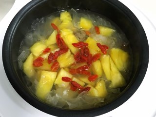 7、桃胶银耳凤梨甜汤,加入凤梨和枸杞子，时间到了即可食用。