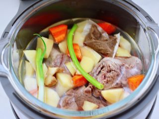 6、筒骨土豆胡萝卜汤,再把切好的土豆块和胡萝卜块也放入，放入炖肉调料包，剩下的葱和姜片，倒入不超过水位线的清水。