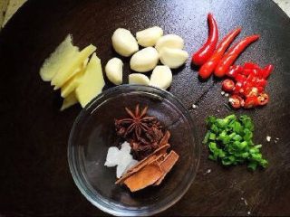 1、家常菜焖猪脚,准备好所有材料，生姜切片，大蒜剥好就行了，葱花，小辣椒两个切成小圈，其余三个小辣椒中间划上一刀就好了，整个的辣椒是炒的时候放的，辣椒圈是出锅放的(不吃辣的可以不加辣椒)