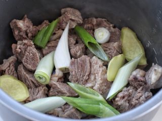 6、清炖牛肉萝卜汤,将牛肉块放入高压锅内胆中，接着放入葱段和姜片