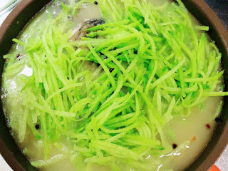 12、萝卜丝鲫鱼汤,放入萝卜丝，继续炖煮。