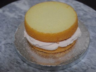 11、巧克力淋面蛋糕,放一片蛋糕片在底座上，抹上淡奶油，加入蜜豆，抹平后盖上一层蛋糕片