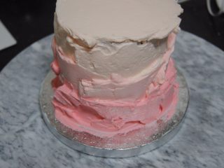 14、巧克力淋面蛋糕,剩余的淡奶油加入细砂糖和一滴红色素打发，取1/3抹在最上面层，剩余的再加入一点点红色素混匀，取出抹在蛋糕边上