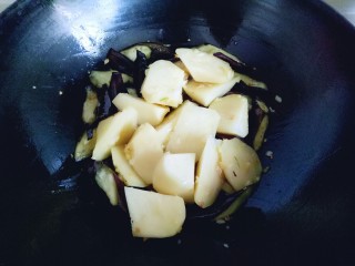 11、土豆茄子白菜煲,倒入土豆继续翻炒。