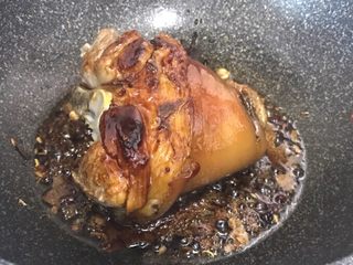 7、秘制酱肘子,出香味后,把肘子放进去,这一步要注意!肘子放进去前最好擦干水分,不然水遇高温的糖和油会噼里啪啦四处乱溅!淋上半碗高度白酒,没有高度白酒的,就用一瓶啤酒,然后煮5分钟,再翻面,同样煮5分钟;
