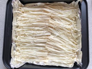 2、蒜香金针菇,金针菇洗净，沥干水份，切掉根部，撕碎摆入铺了锡纸的方形烤盘中