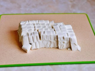 4、平菇豆腐汤,豆腐倒扣在砧板上,再切小块。