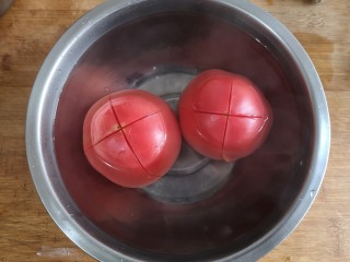 3、金针菇番茄龙利鱼,2个大番茄顶部划十字，顶部朝下放进碗中浇开水烫2-3分钟后剥去皮。