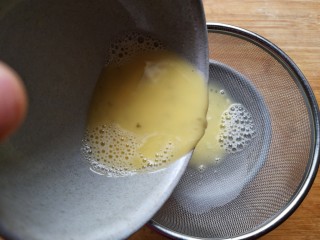 8、虾仁蒸蛋羹,将打好的蛋液过筛，将表面的泡泡滤出。这一步很关键哦，如果没捞滤出泡泡，那么有泡泡的地方蒸熟了是有很多小坑的，而且蛋液表面也不平整。