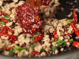 9、干煸豆角,接着加入郫县豆瓣酱炒出红油。