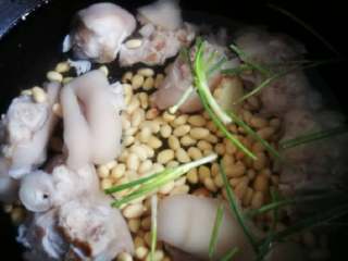 5、猪蹄黄豆汤,炖猪蹄最好用砂锅,我用了铸铁锅,相比能最佳程度的保留食物的原汁原味。在锅里放入焯水后的猪蹄,浸泡好的黄豆,葱段姜片,一次性加入适量清水(一次性是指中途不能再添加水)。