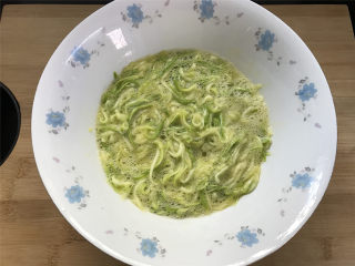 6、西葫芦鸡蛋饼,用筷子把打入的鸡蛋和西葫芦丝搅抖均匀。