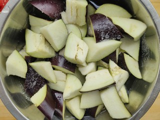 2、西红柿烧茄子,将茄子先切条再滚刀切成块，放入盆中加入盐腌制，使茄子中多余的水稀释出来，这样不至于水唧唧的口感。