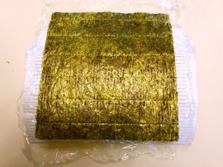 14、寿司,再取一片海苔,粗面向上放在保鲜膜上