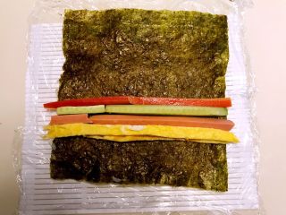 20、寿司,把紫菜翻身,有米饭的一面向下,在紫菜上加入蛋皮,火腿条,瓜条和胡箩卜条