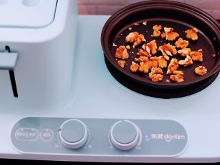 6、百合酒酿苹果核桃羹,启动东菱早餐机的煎锅，小火慢慢把核桃炒香后盛出备用。