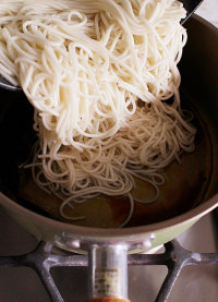 11、葱油酥香干拌面,捞起的挂面放入做法9的油锅中,开小火将酱汁与面条拌匀,