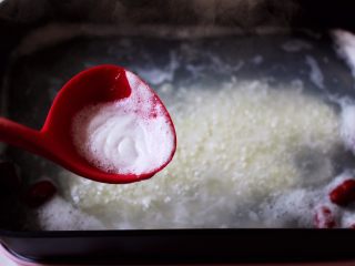 7、双色红薯糯米粥,用勺子撇去锅中的浮末。