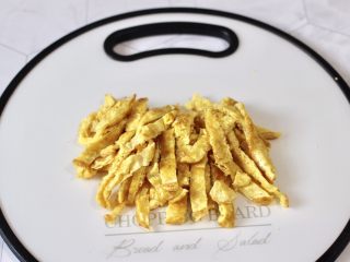 6、海鲜菇鸡蛋汤,把炒熟的鸡蛋,用刀切宽丝备用。
