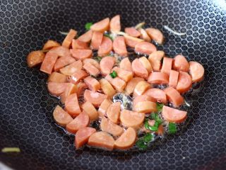 7、海鲜菇鸡蛋汤,锅中倒入剩下的5克花生油烧热,大火爆香葱姜后,放入火腿片大火快速翻炒至变软。