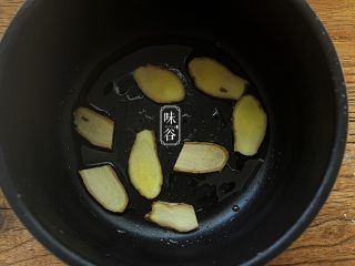 5、简单方便的电饭煲可乐鸡翅,在电饭锅里倒入1汤匙食用油，放进姜片抹匀油；