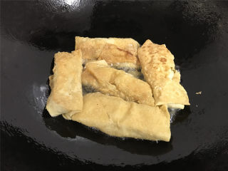 8、豆腐皮包肉,转中火，一面煎好后翻面再煎另一面，直至两面煎至金黄色。