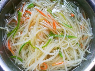 5、超爽口的凉拌土豆丝,放入胡萝卜丝和辣椒丝煮一分钟,然后捞出沥干水。和土豆丝一起放入盆中备用。