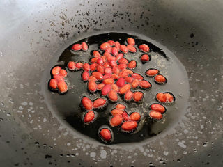 7、芹菜拌腐竹,倒入花生米，不断的用炒勺翻炒花生米，一定记得用小火。